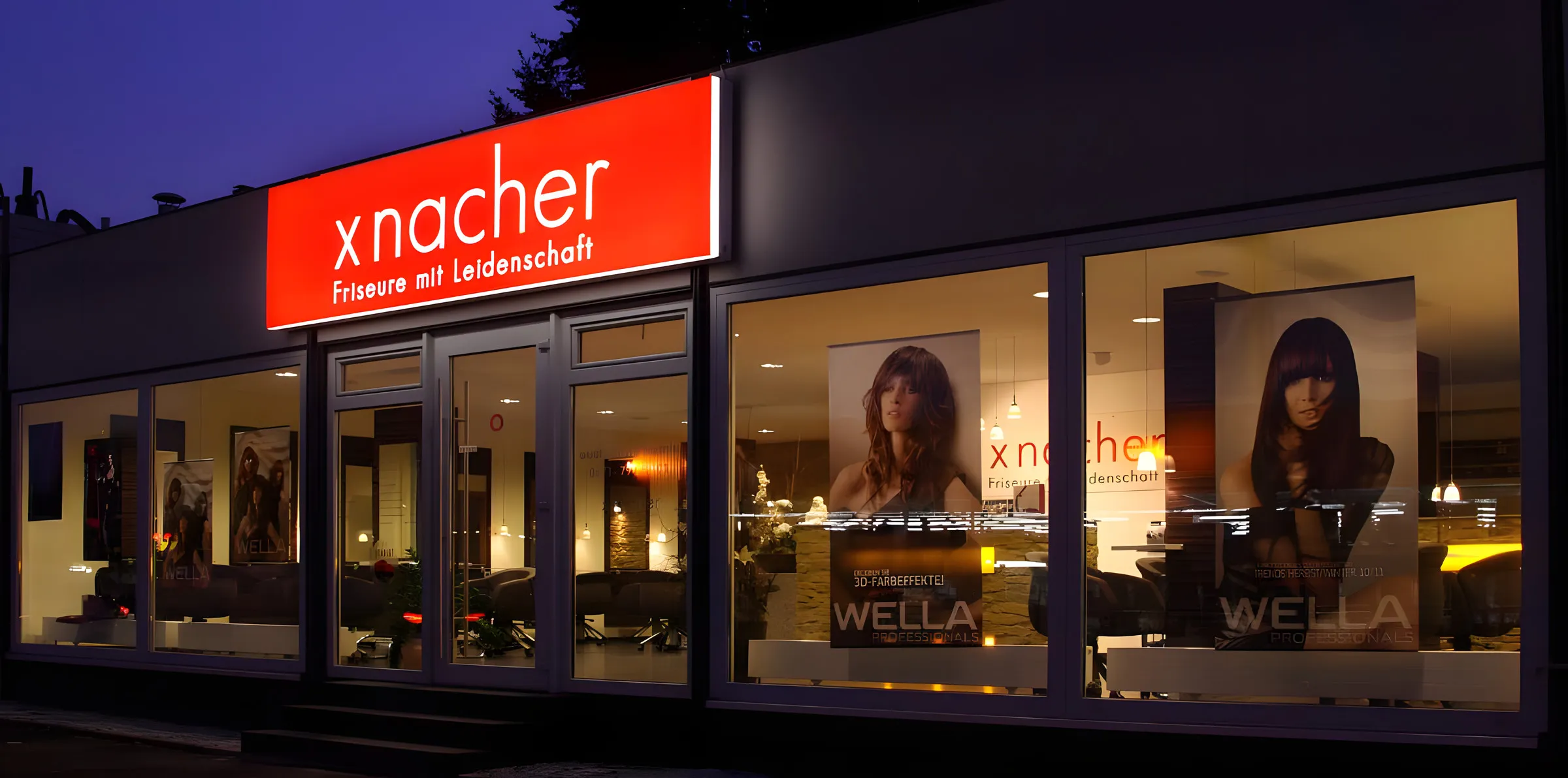 Außenansicht des Salons am Abend mit leuchtendem xnacher-Schild