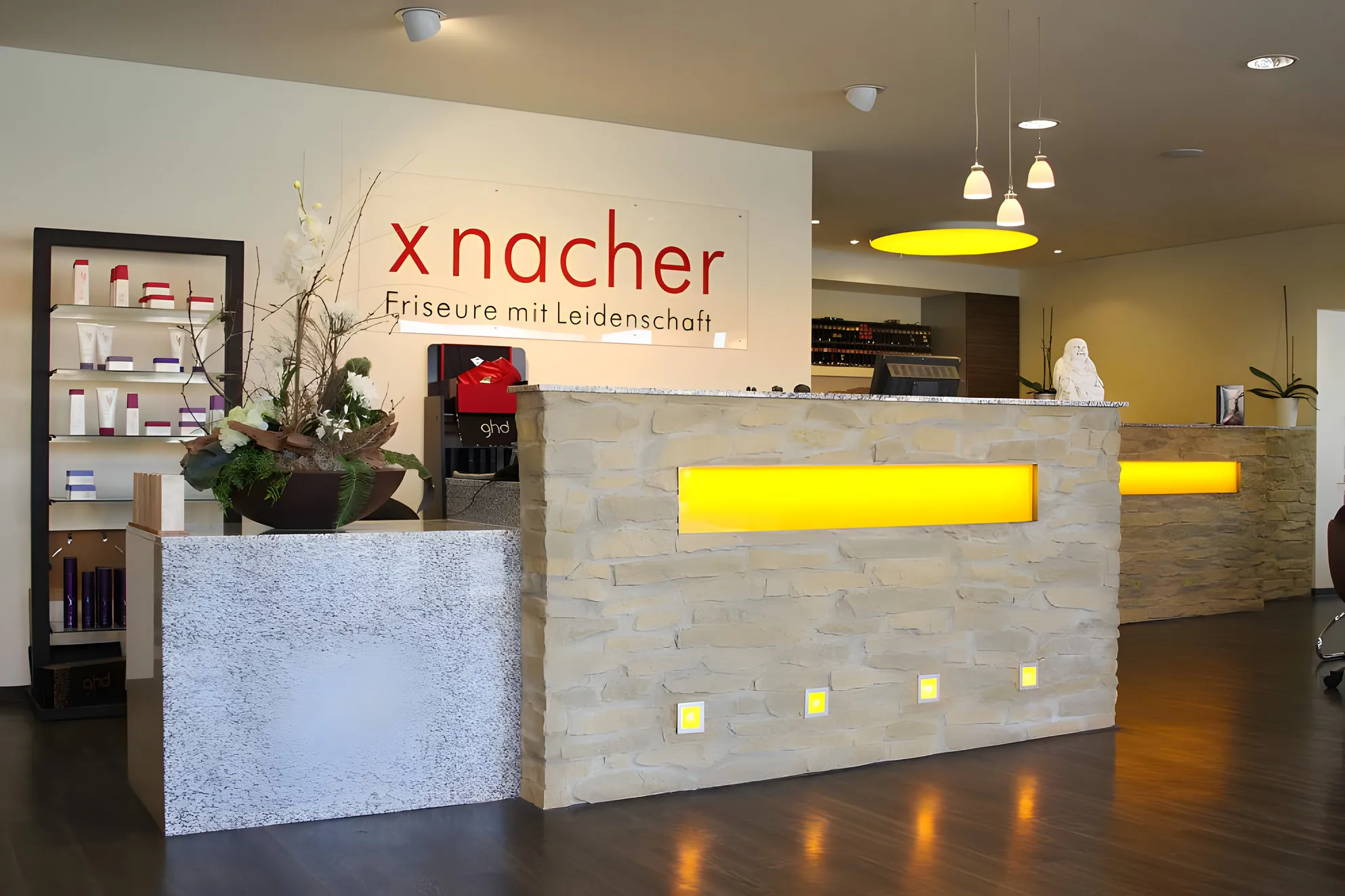 Empfangsbereich des Salons mit Natursteintresen und Produktregal